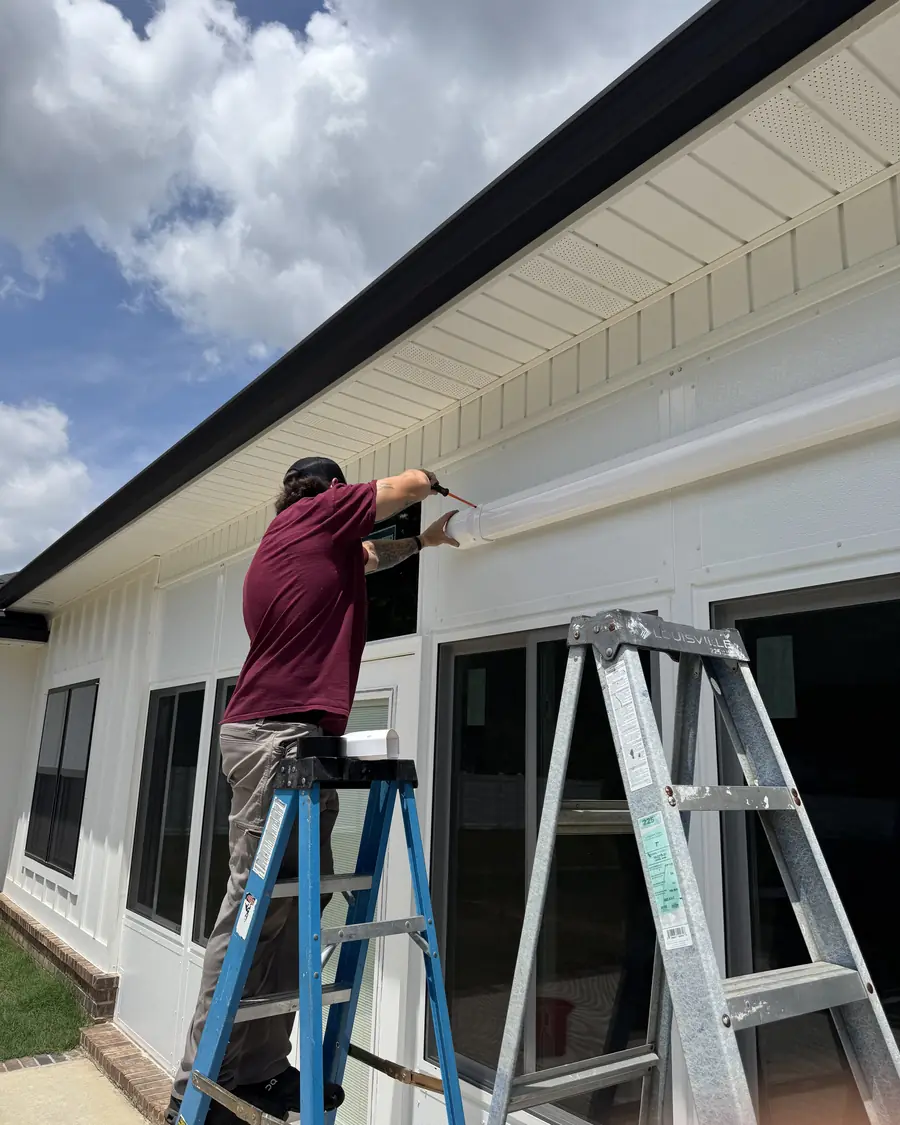 A Wingate's Air Conditioning technician sealing an exterior soffit on a home in Milton, FL