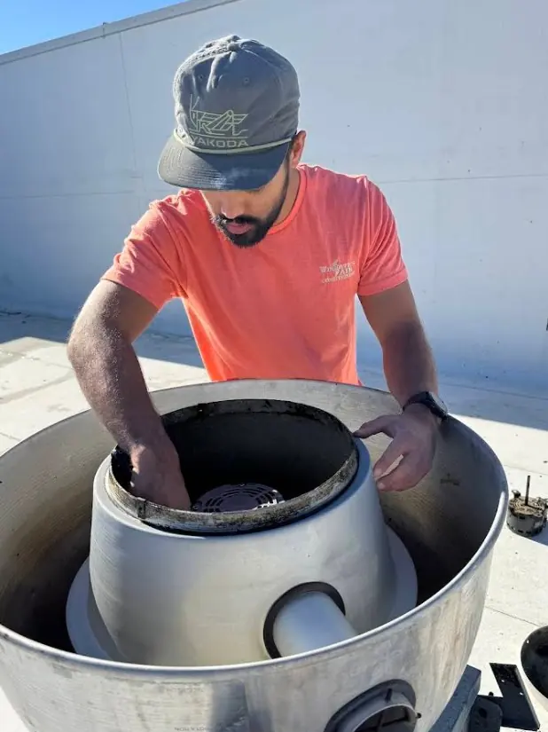 A Wingate's Air Conditioning technician working inside a rooftop unit near Cantonment, FL