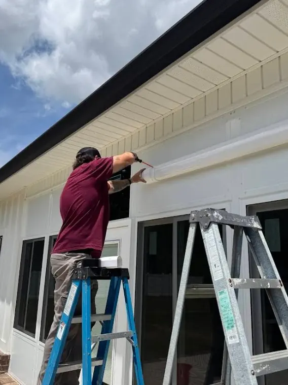 A Wingate's Air Conditioning technician on a ladder working on the exterior of a home in Pace, FL